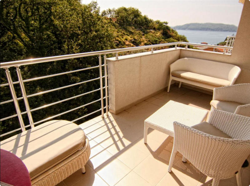 Cozy balcony with wicker furniture and a sea view in an apartment in Bečići, Montenegro. Modern metal railing.