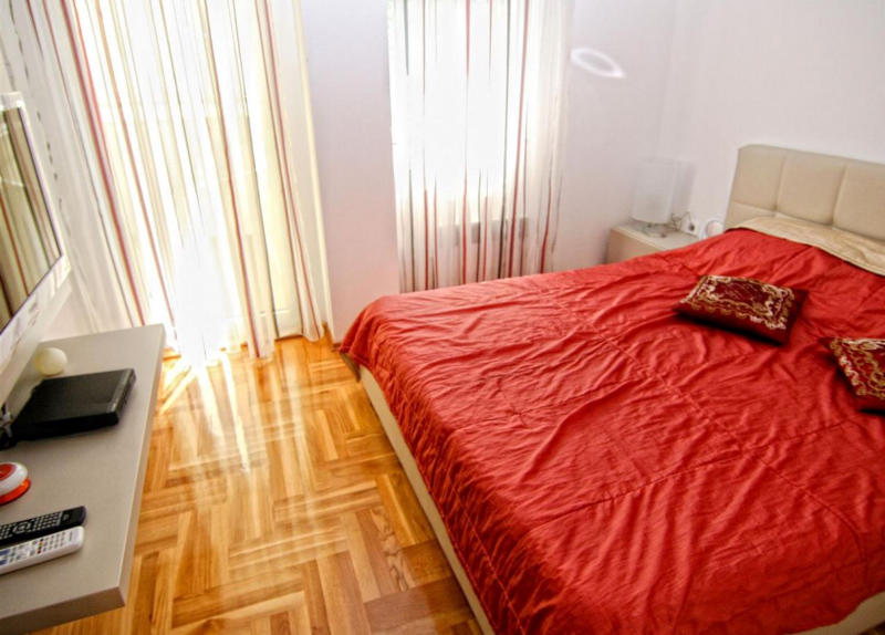 Bright bedroom with a double bed, parquet flooring, and panoramic windows in an apartment, Becici, Montenegro.