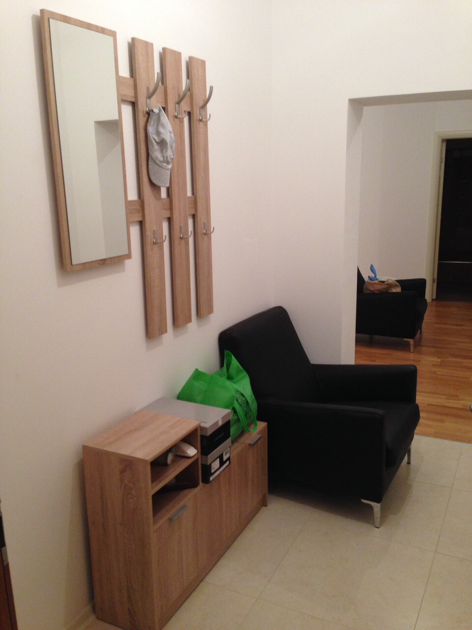 Hallway in an apartment in Bečići, Montenegro: a wooden coat rack with a mirror, a shoe cabinet, and a black armchair.