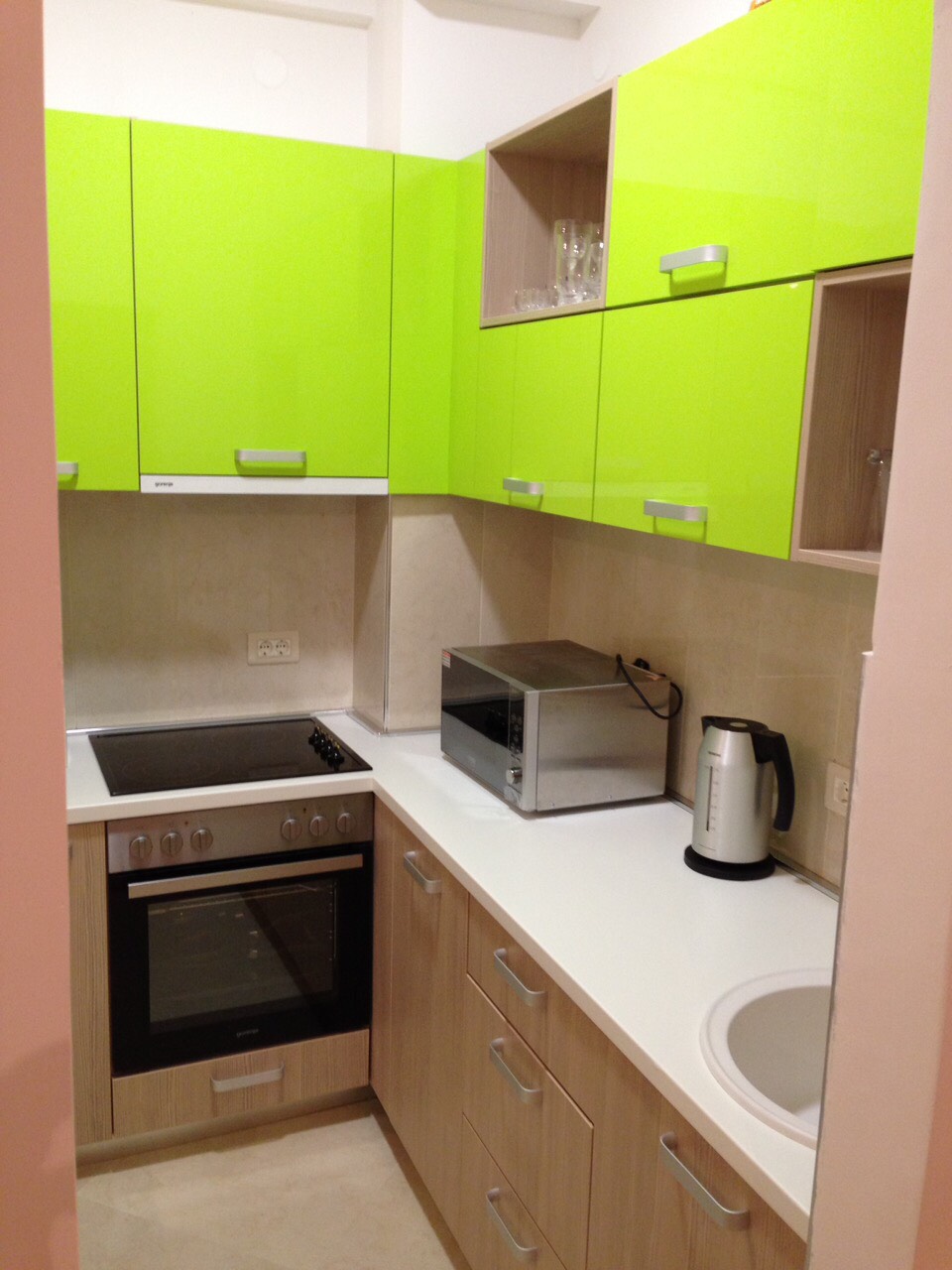 Modern kitchen with bright green fronts in an apartment for sale in Bečići, Montenegro: built-in appliances and stove.
