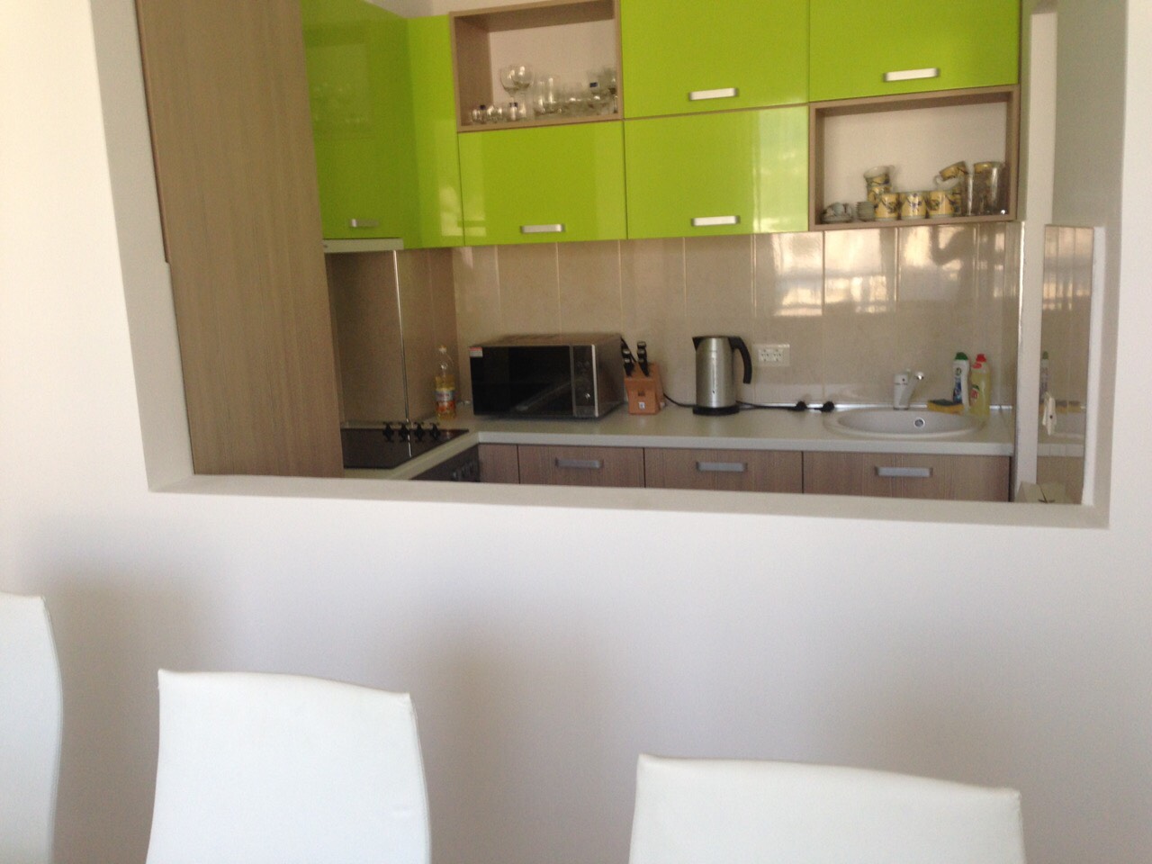 Modern kitchen with bright green fronts in an apartment for sale, Bečići, Montenegro: view of the work area and appliances.