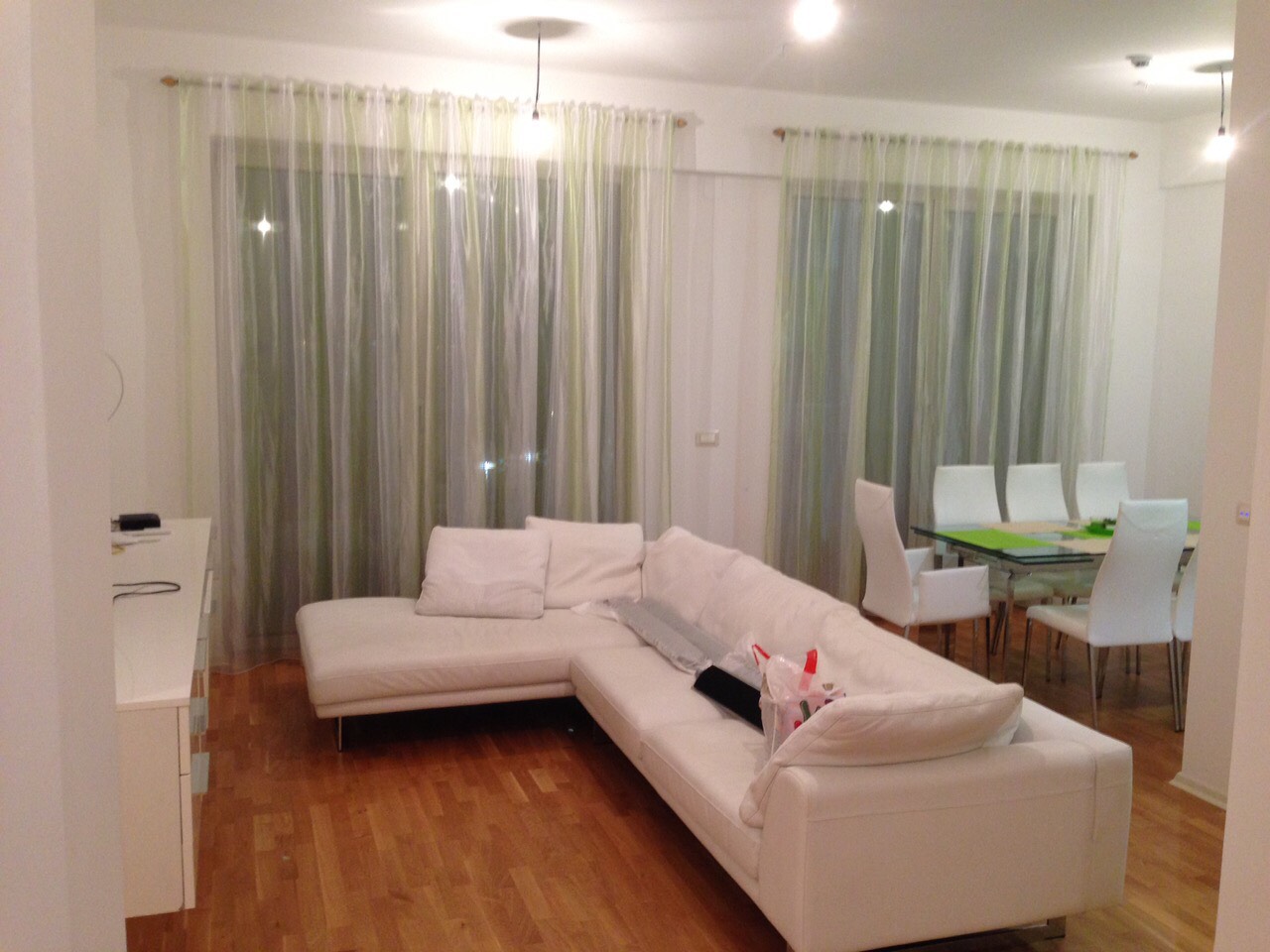 Living room in an apartment in Bečići, Montenegro: white corner sofa, dining area, bright interior, and panoramic windows.