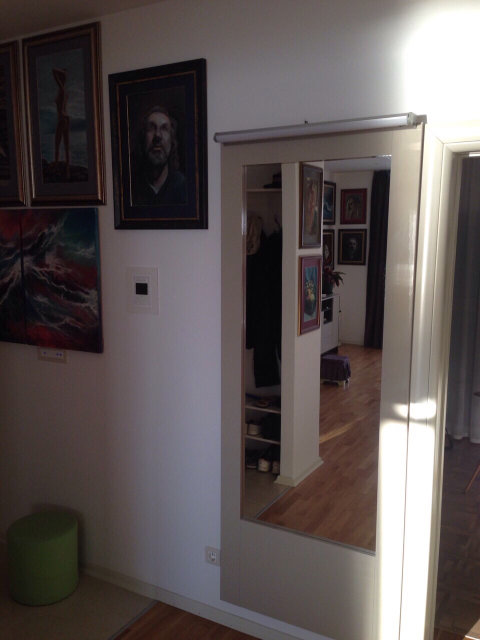 Hallway interior with a mirrored wardrobe and paintings in an apartment in Bečići, Montenegro. Bright design, parquet flooring.