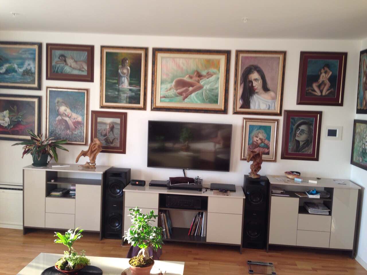 Living room in an apartment in Bečići, Montenegro: a wall with a collection of paintings, modern furniture, and a TV in the interior.
