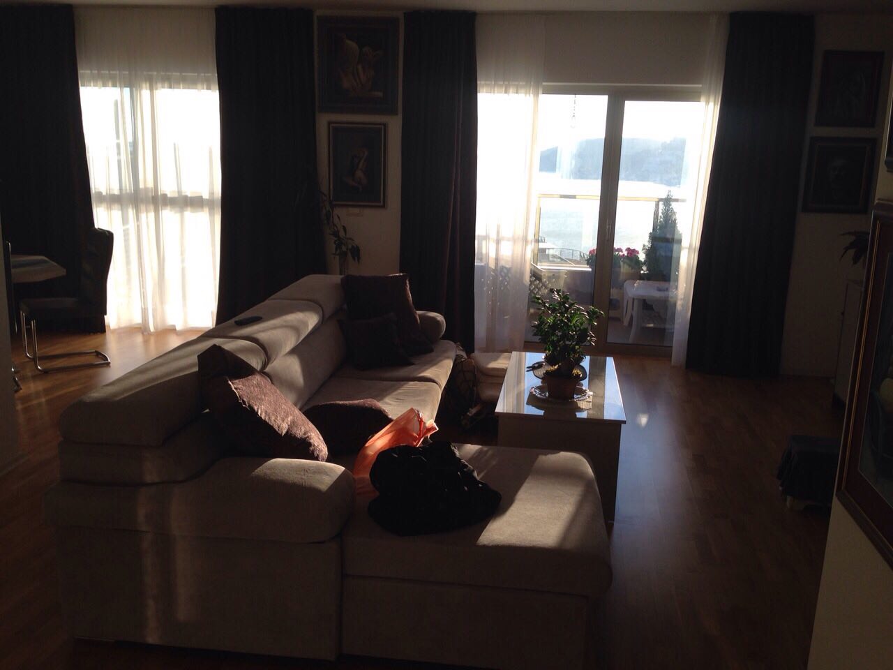 Living room in an apartment in Bečići, Montenegro: a light-colored sofa, coffee table, and access to a terrace with sea views.