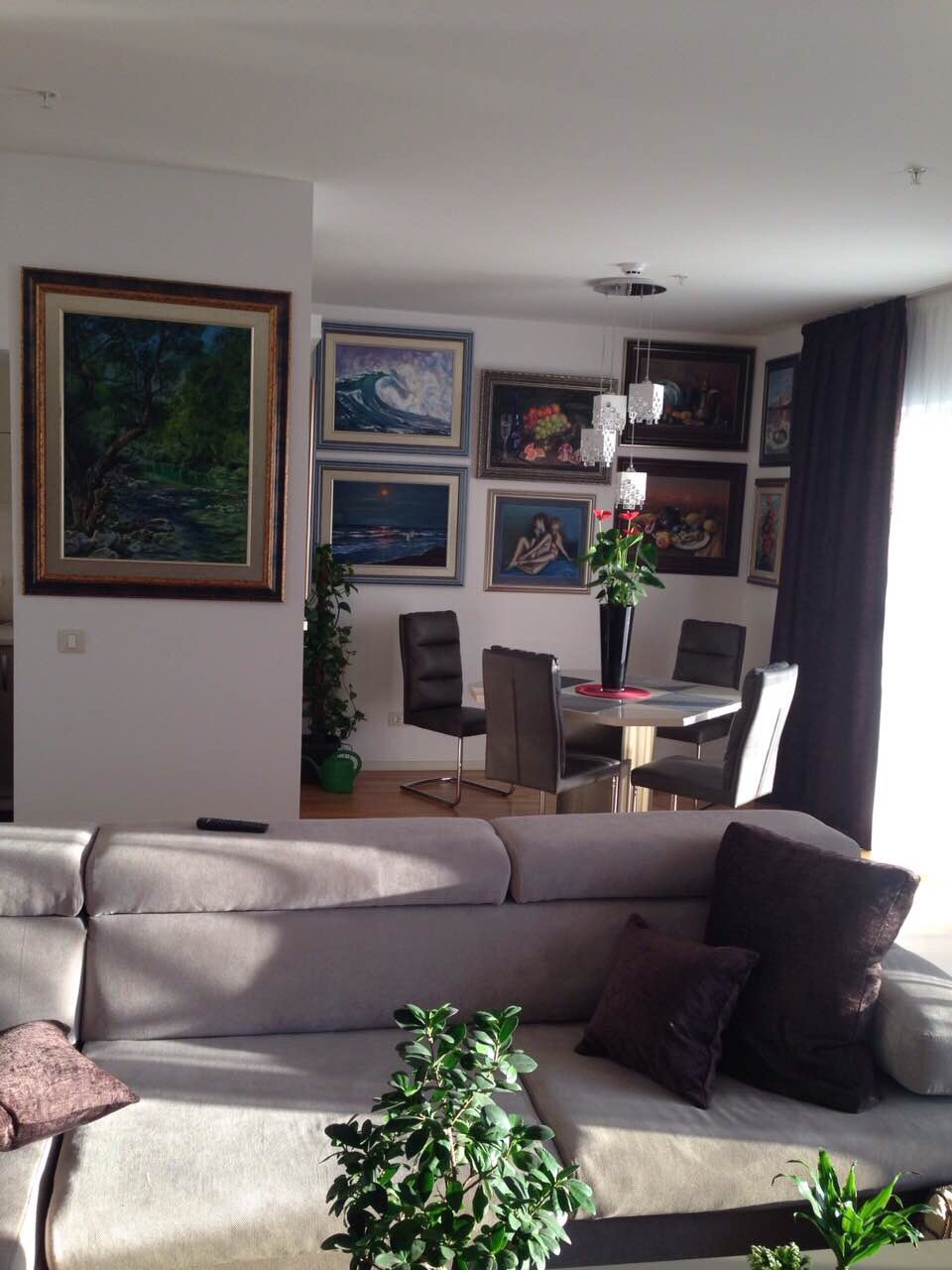 Living room with a soft sofa and dining area in an apartment in Bečići, Montenegro, decorated with paintings on the walls.