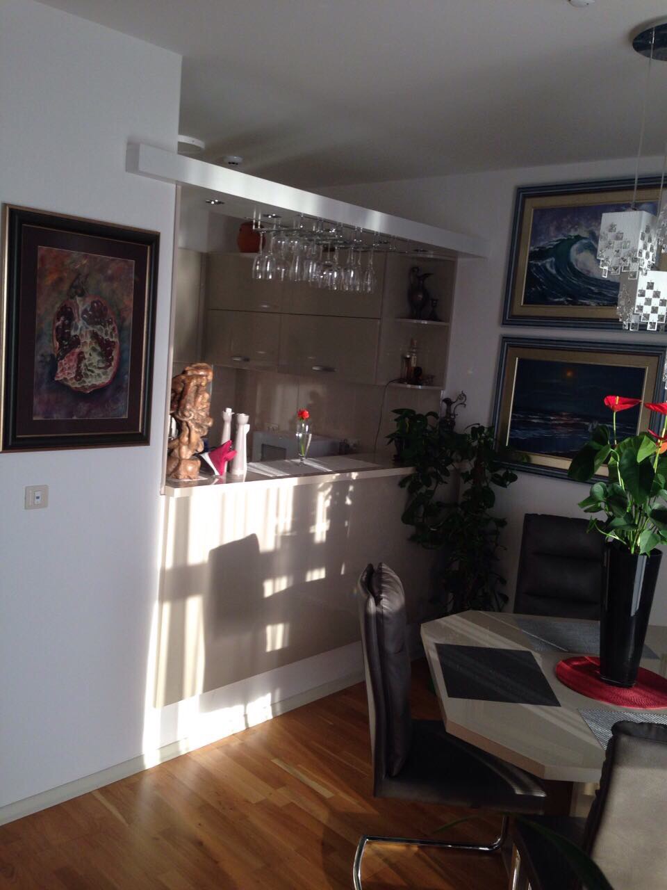 Living room with a bar counter and dining area in an apartment in Bečići, Montenegro: modern interior with paintings.