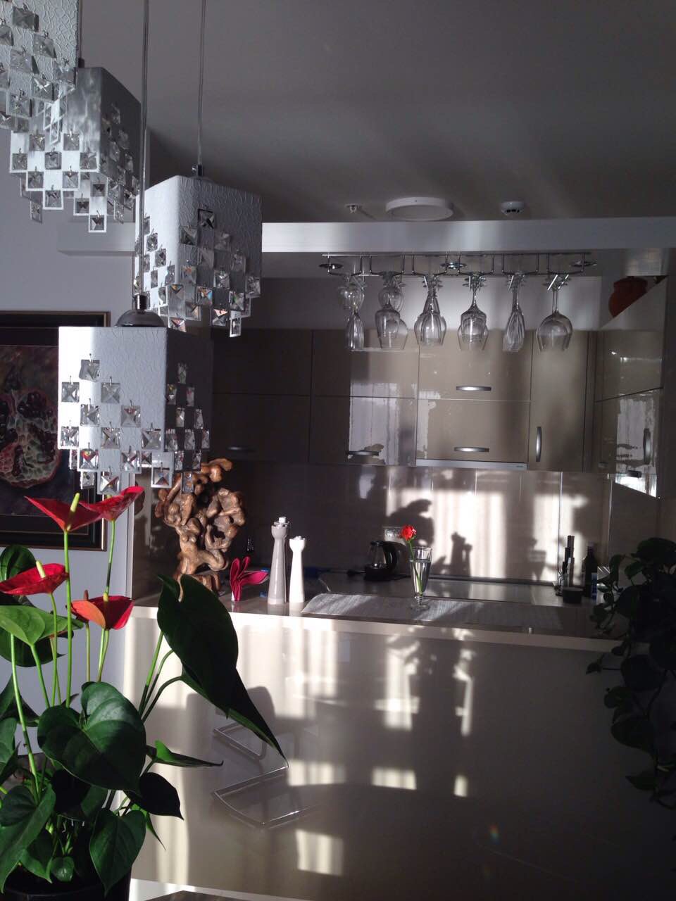 Modern kitchen in an apartment in Bečići, Montenegro: glossy fronts, pendant lights, and a wine glass holder.