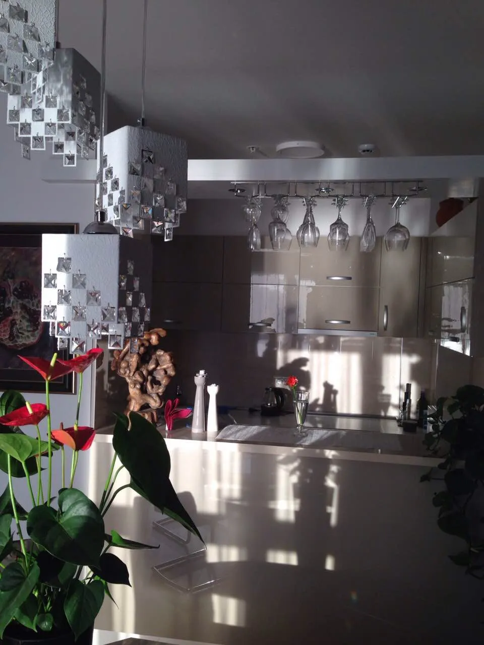 Modern kitchen with glossy countertop, hanging cabinets, and an inverted wine glass rack.