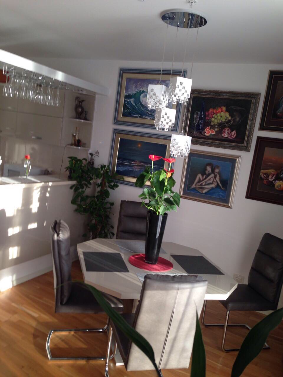 Living room with dining area in an apartment in Bečići, Montenegro: modern furniture, artwork decor, and stylish lighting.