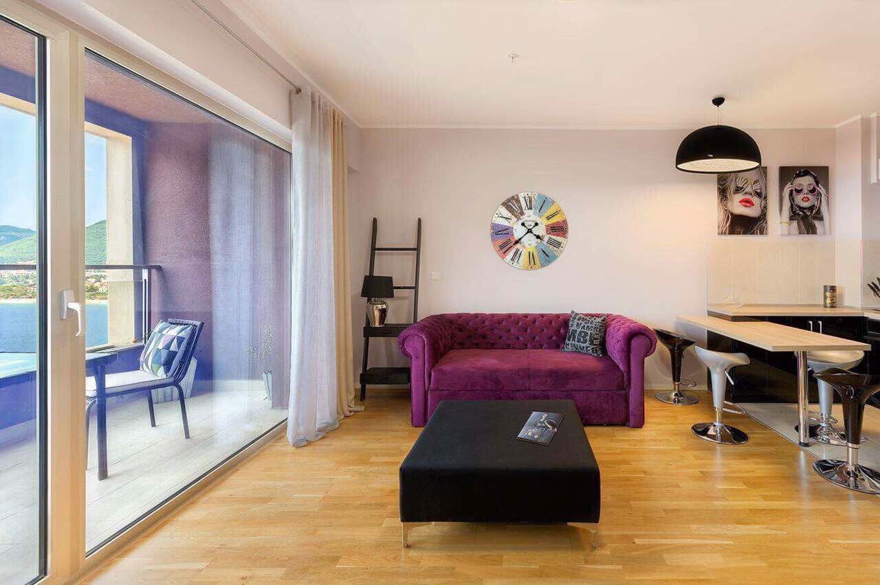 Living room with a purple sofa and panoramic sea view in an apartment, Becici, Montenegro.