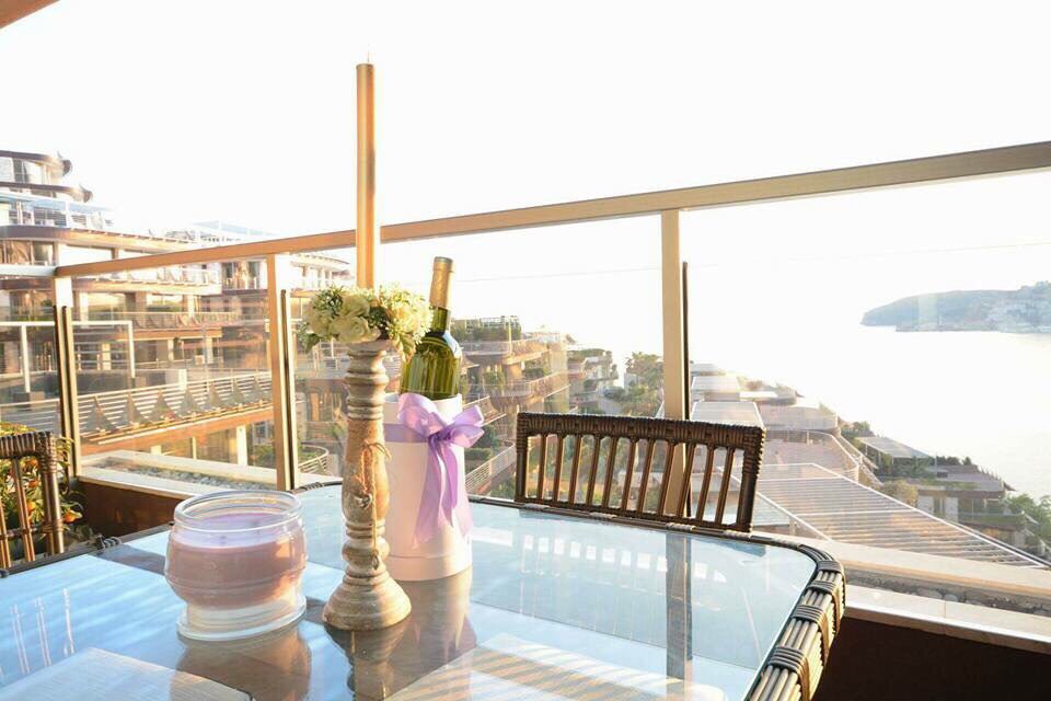Balcony with wicker furniture and sea view in an apartment in Bečići, Montenegro. Table with decor and panoramic glazing.