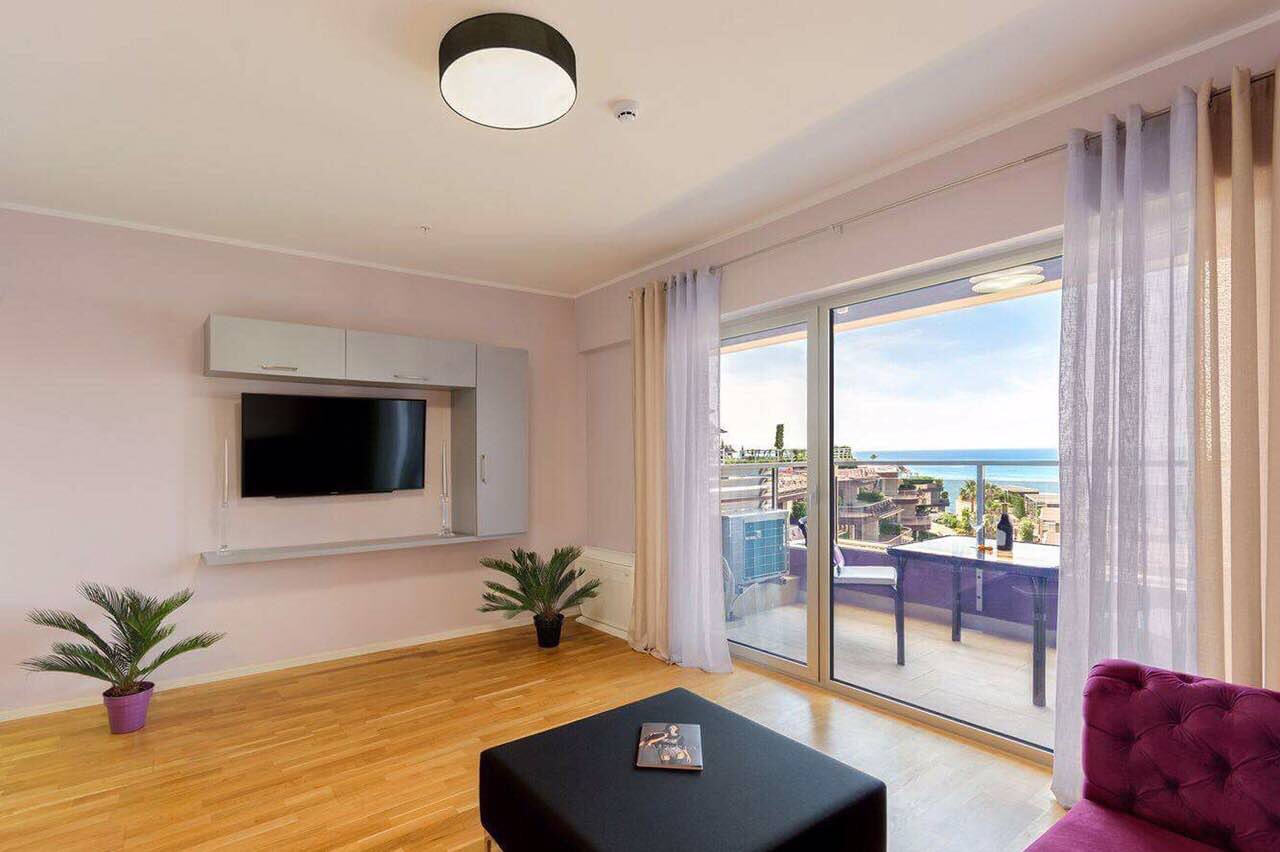 Living room in an apartment in Bečići, Montenegro: modern furniture, TV area, and panoramic sea view from the terrace.