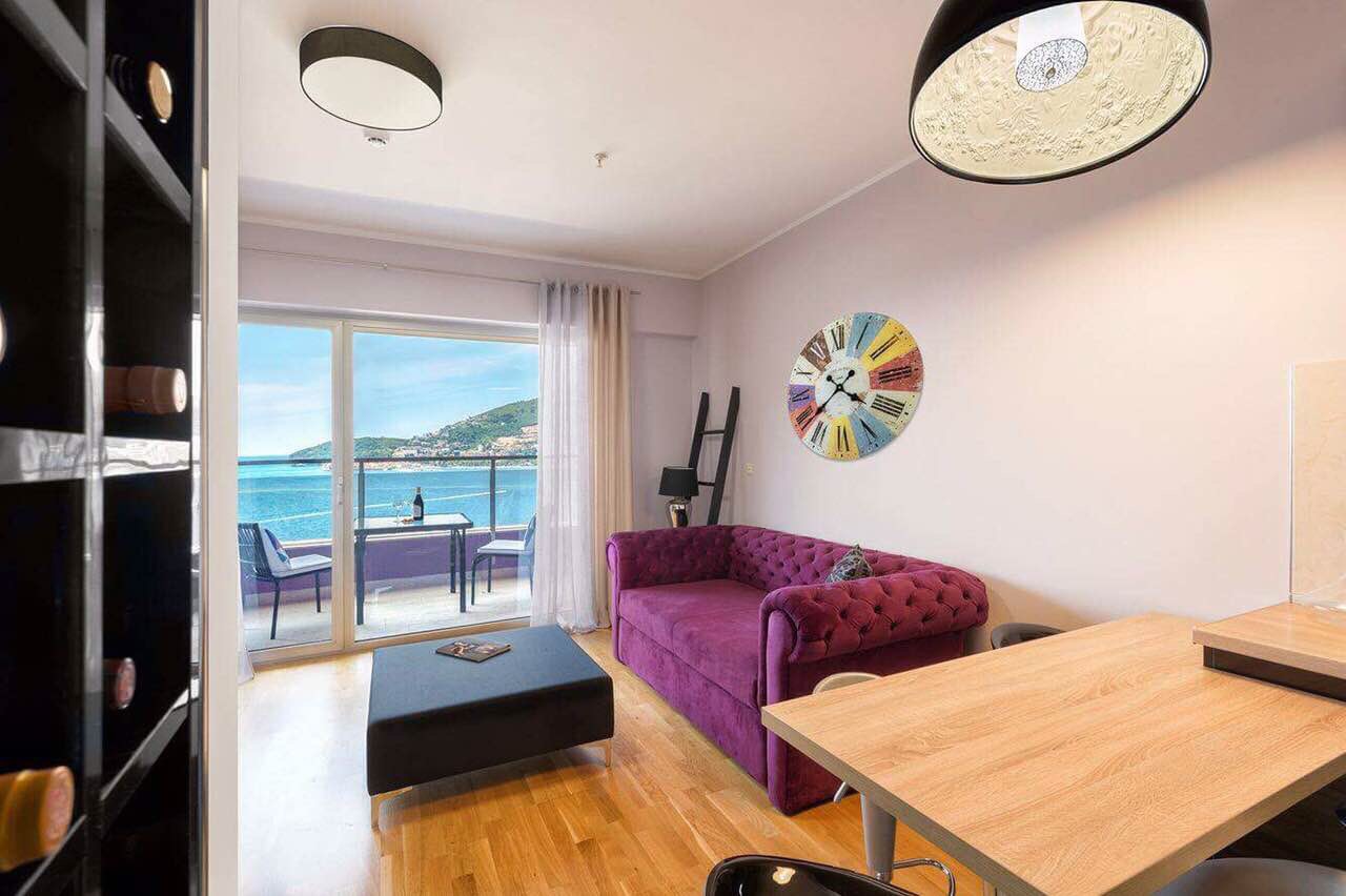 Living room with a purple sofa and sea view in an apartment in Becici, Montenegro: modern interior with a terrace.