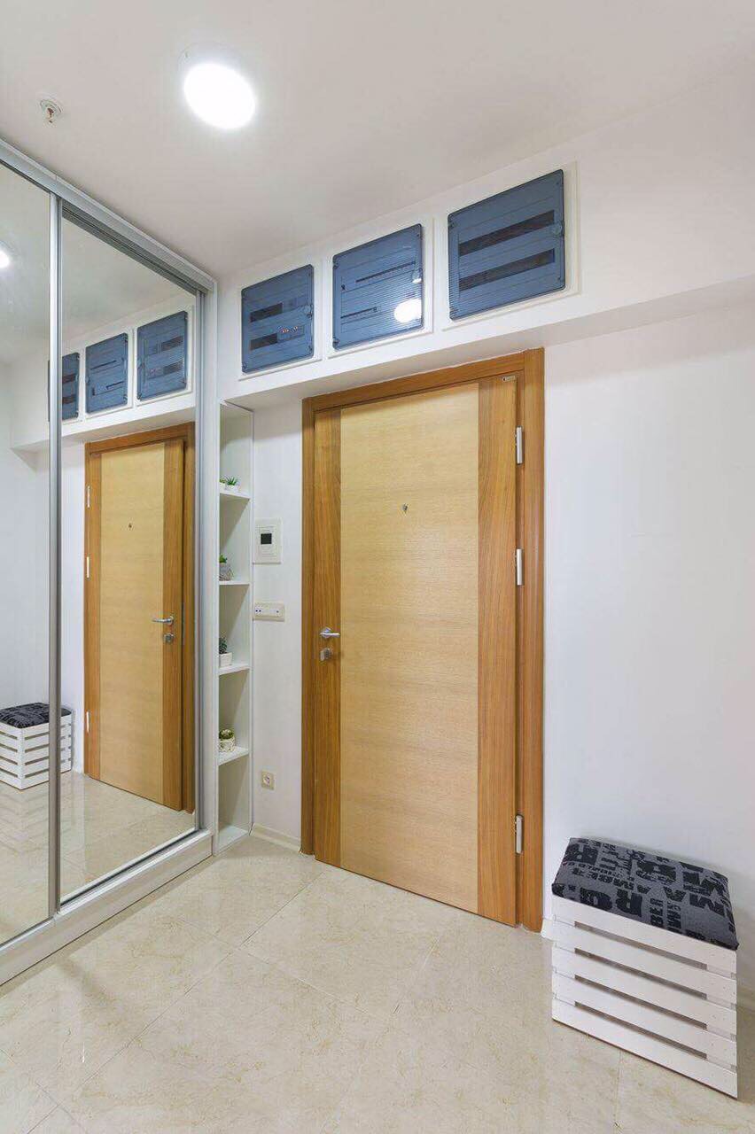 Hallway in an apartment in Bečići, Montenegro: light finishes, built-in mirrored wardrobe, and a wooden front door.