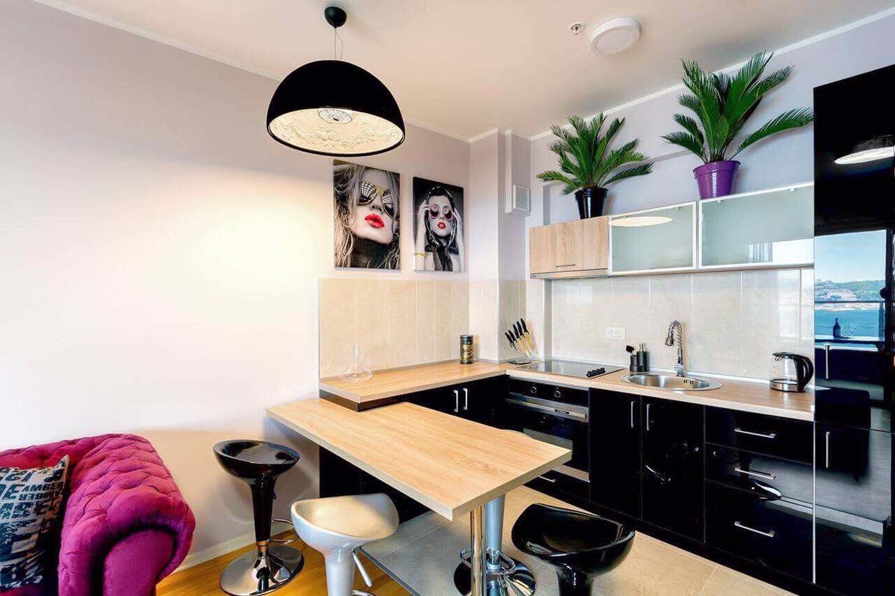 Modern kitchen in an apartment in Bečići, Montenegro: black cabinetry, a bar counter, and sea view from the window.