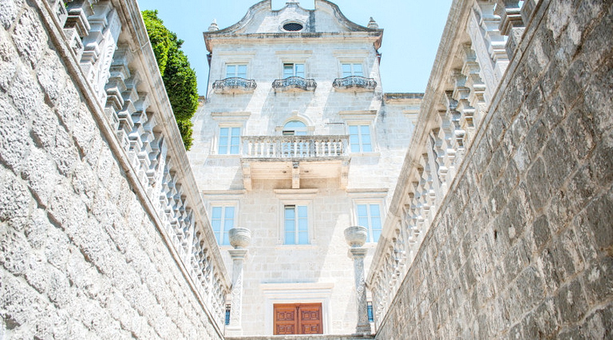 Historic stone villa in Dobrota, Montenegro: facade with balconies, carved railings, and a grand staircase.