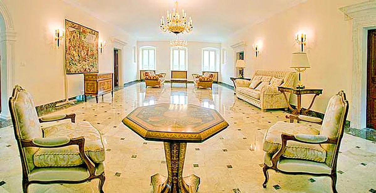 Elegant large room with marble floors, chandelier, sofa, and armchairs in a classic style.