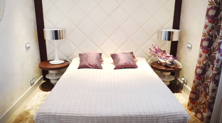 Cozy bedroom with a double bed and soft headboard in a villa in Tivat, Montenegro. Modern interior.