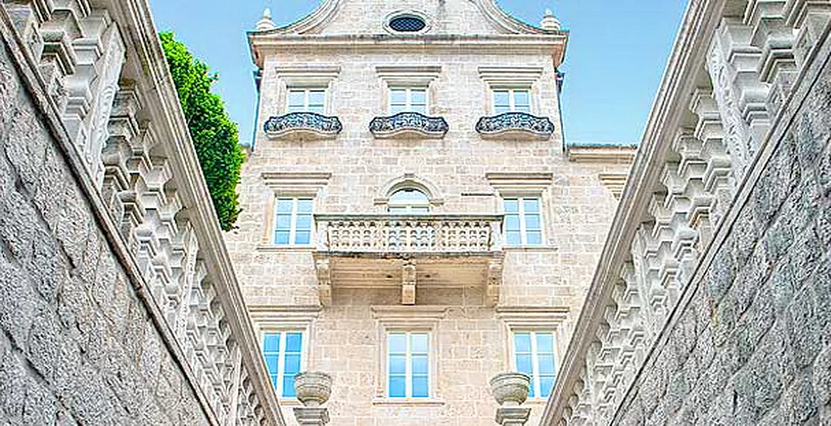 Low angle view of a historic stone building facade featuring balconies and windows between two walls.