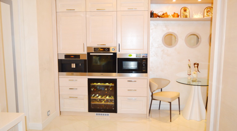 Modern kitchen in a villa in Tivat, Montenegro: built-in appliances, wine cooler, and dining area with a glass table.