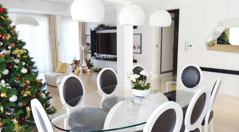 Modern living room with dining area in a villa in Tivat, Montenegro: glass table, designer chairs, and a Christmas tree.