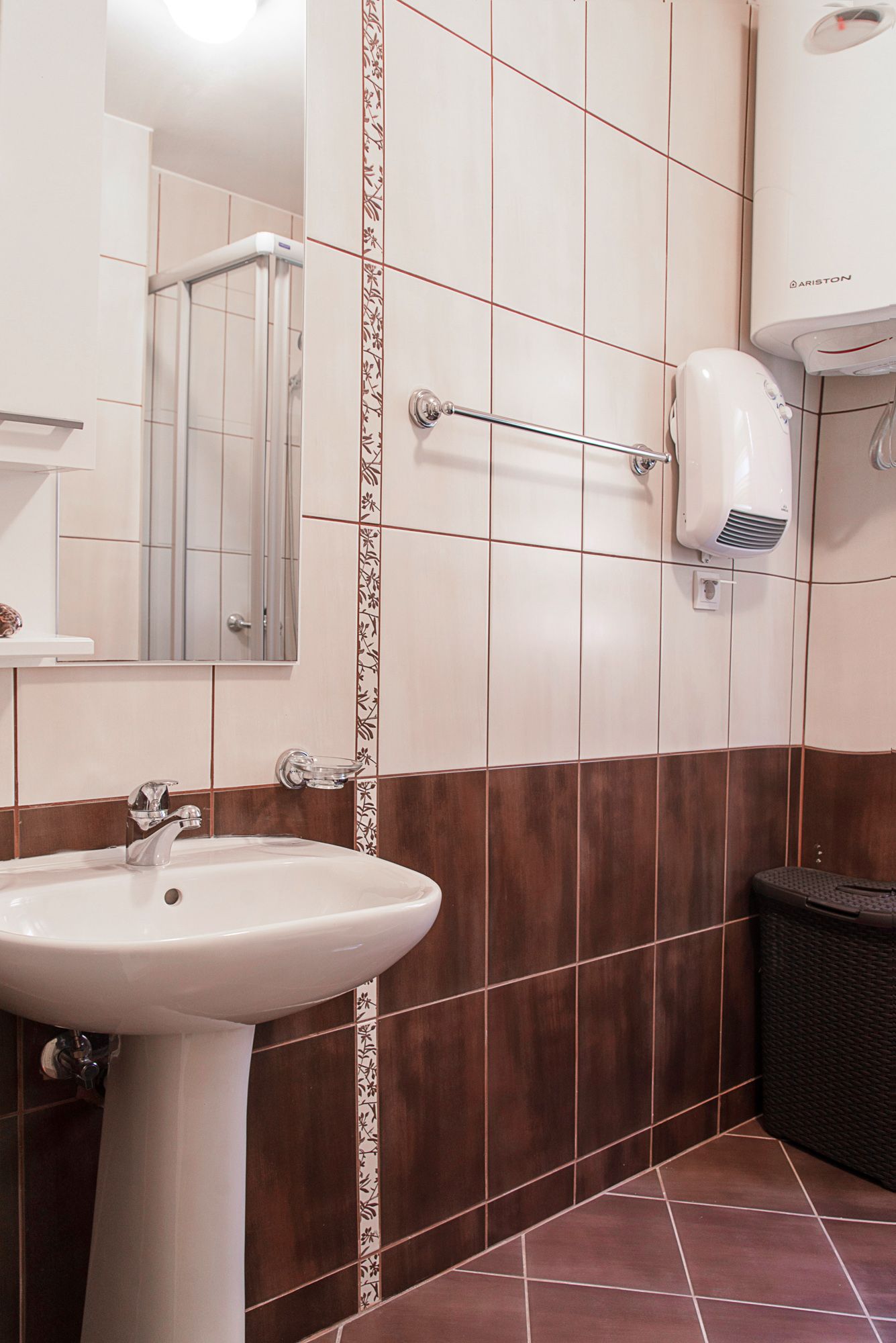 Bathroom in a townhouse in Lastva, Montenegro: light tile, sink, mirror, and an Ariston water heater.