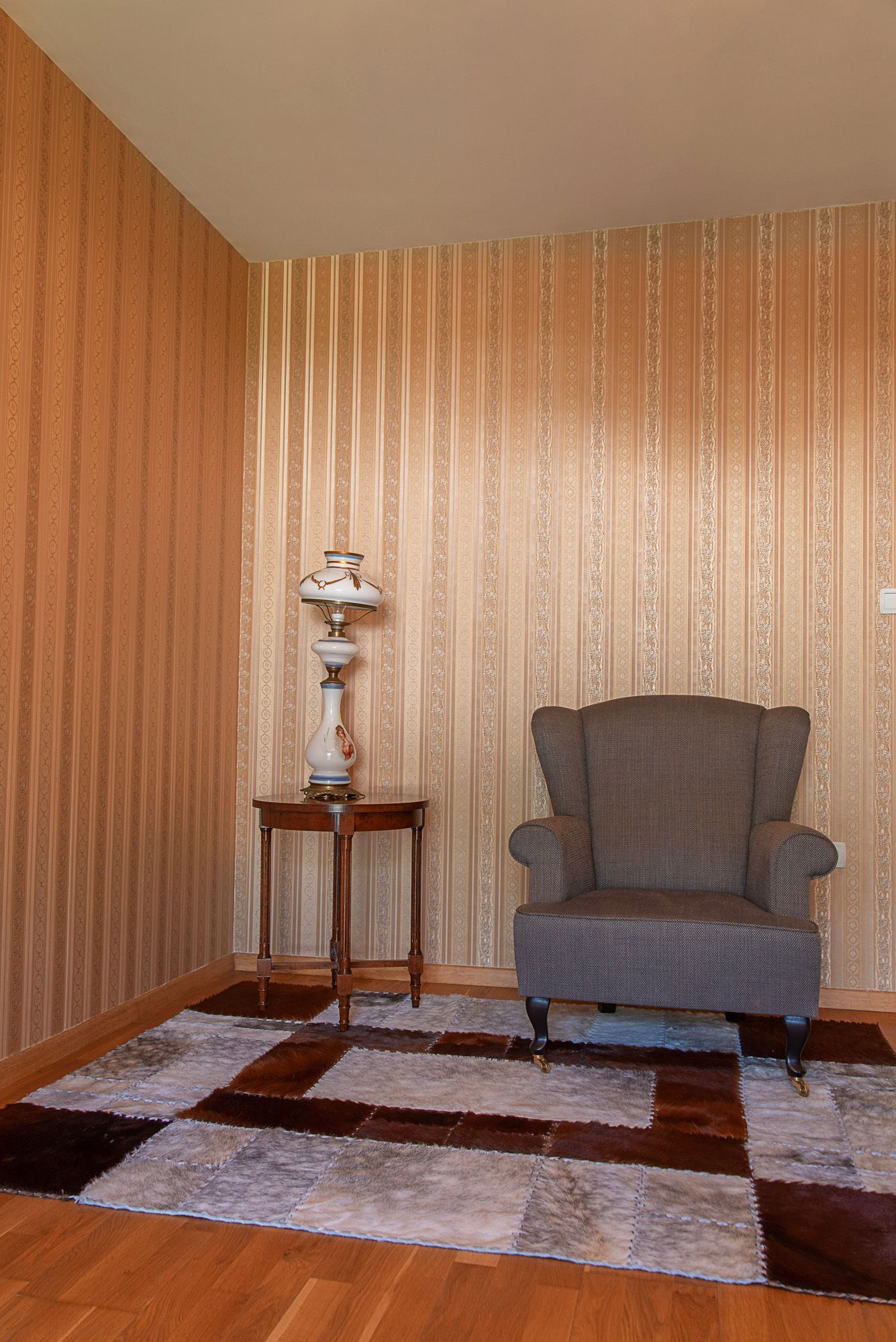 A cozy relaxation corner in the townhouse living room in Lastva, Montenegro: an armchair, a vintage lamp, and a fur rug.