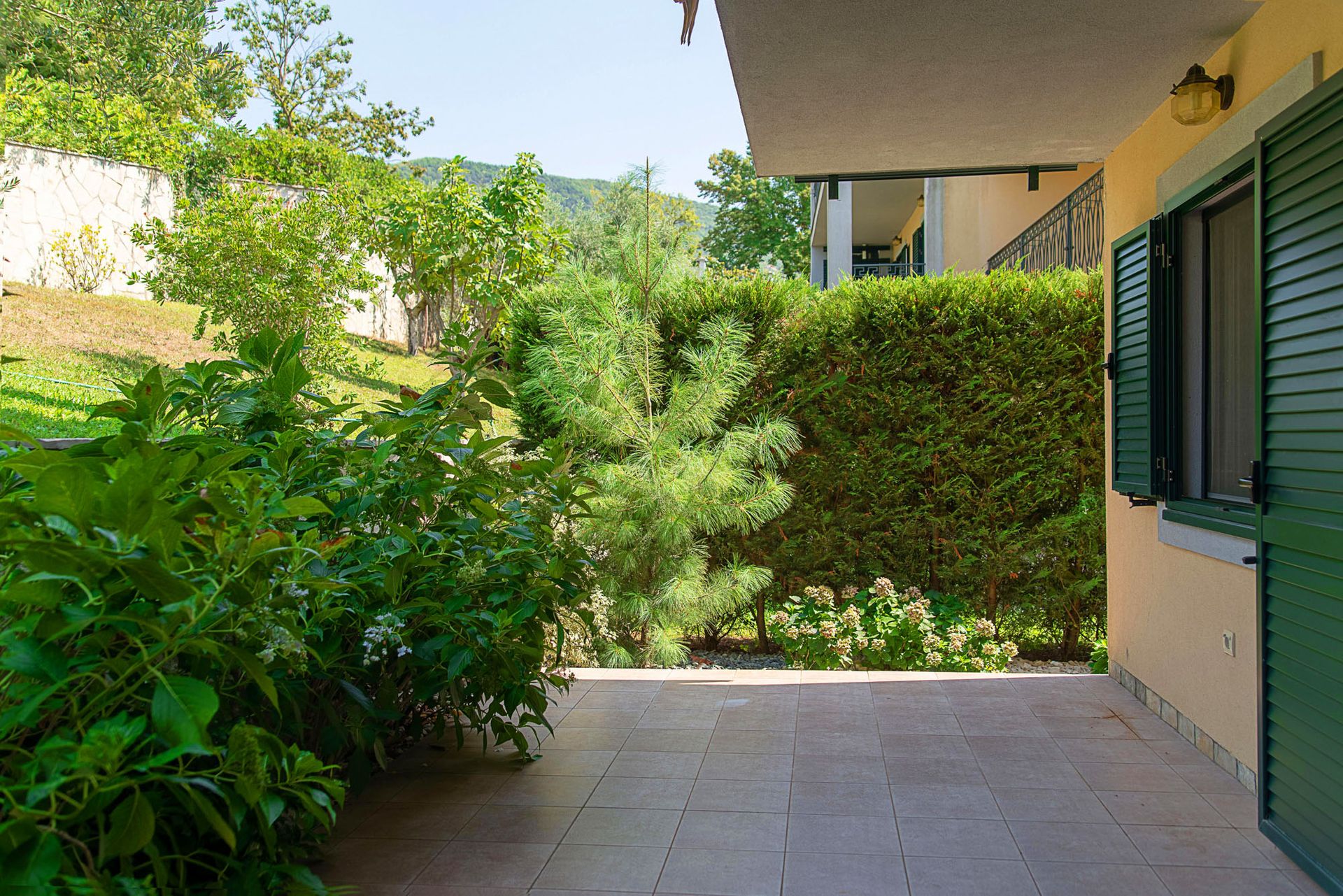 Cozy townhouse terrace in Lastva, Montenegro, with access to a private green garden and mountain views.