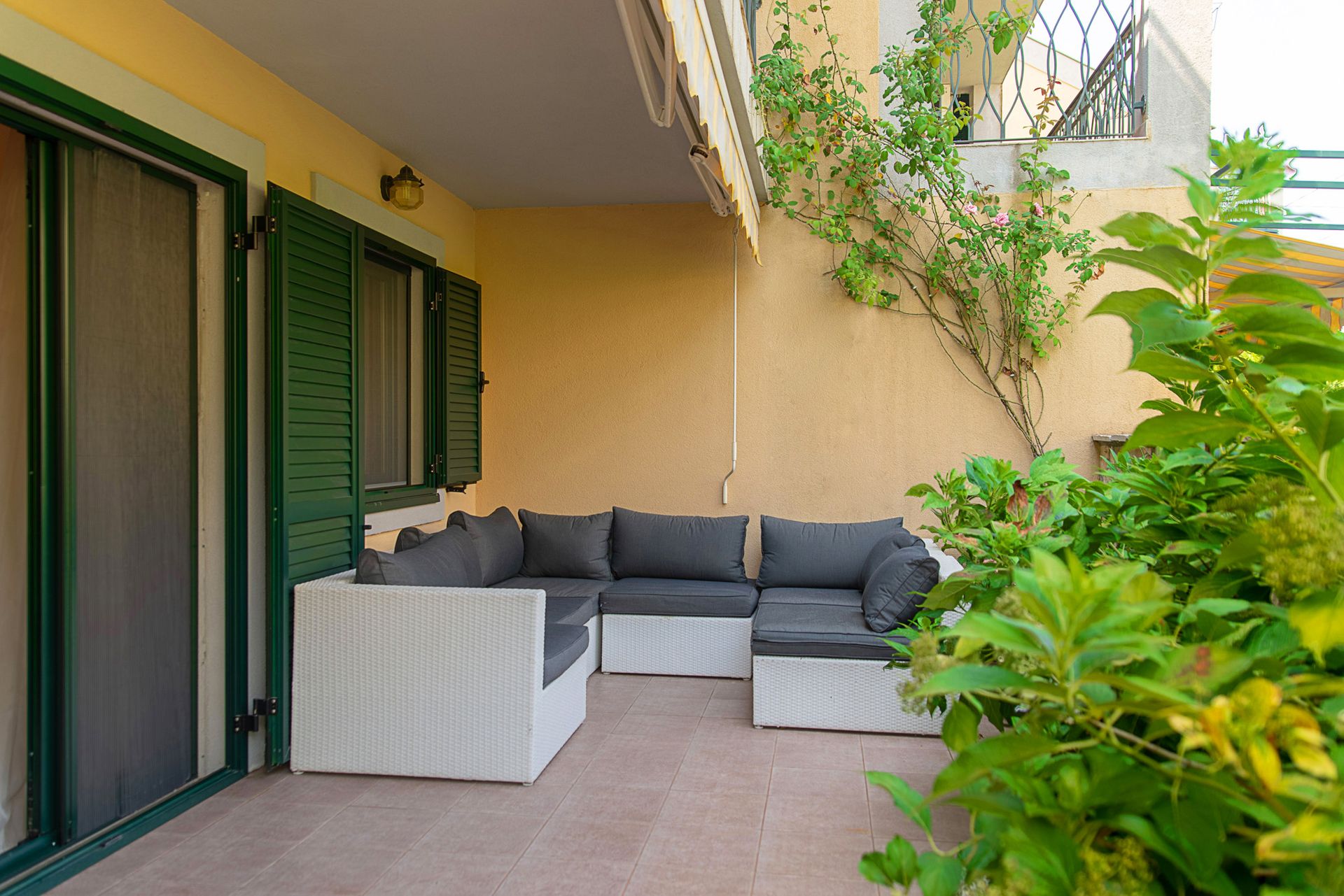 Cozy terrace with wicker furniture and green shutters in a townhouse, Lastva, Montenegro.