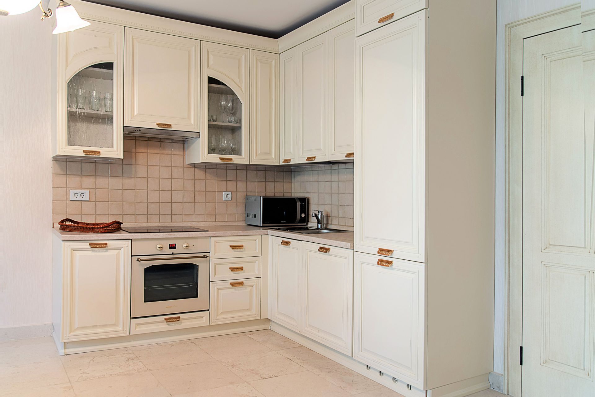 Bright classic kitchen with appliances in a townhouse, Lastva, Montenegro: built-in cabinetry and tiled backsplash.
