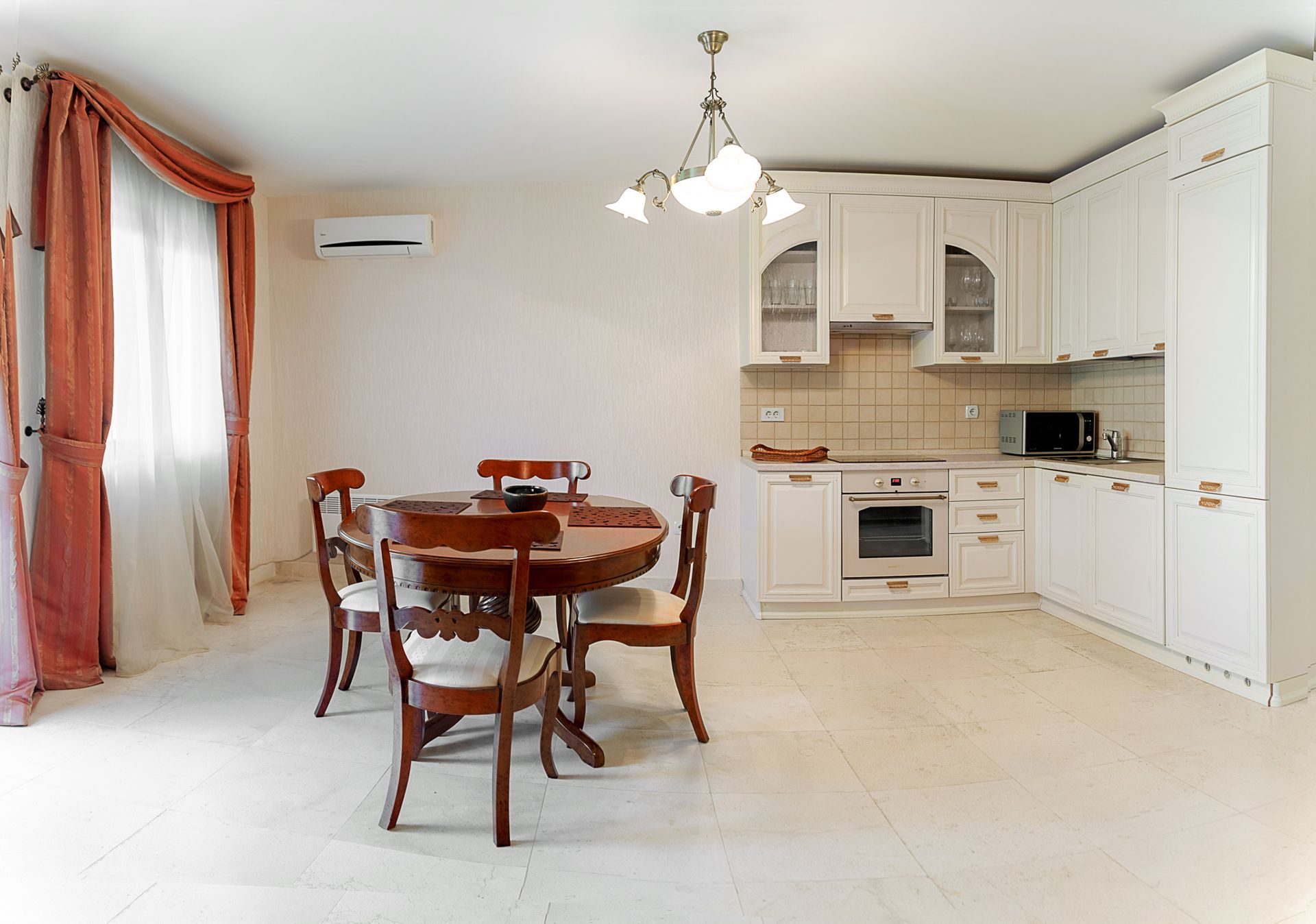 Bright kitchen-dining room with a white fitted kitchen and a wooden dining table in a townhouse, Lastva, Montenegro.