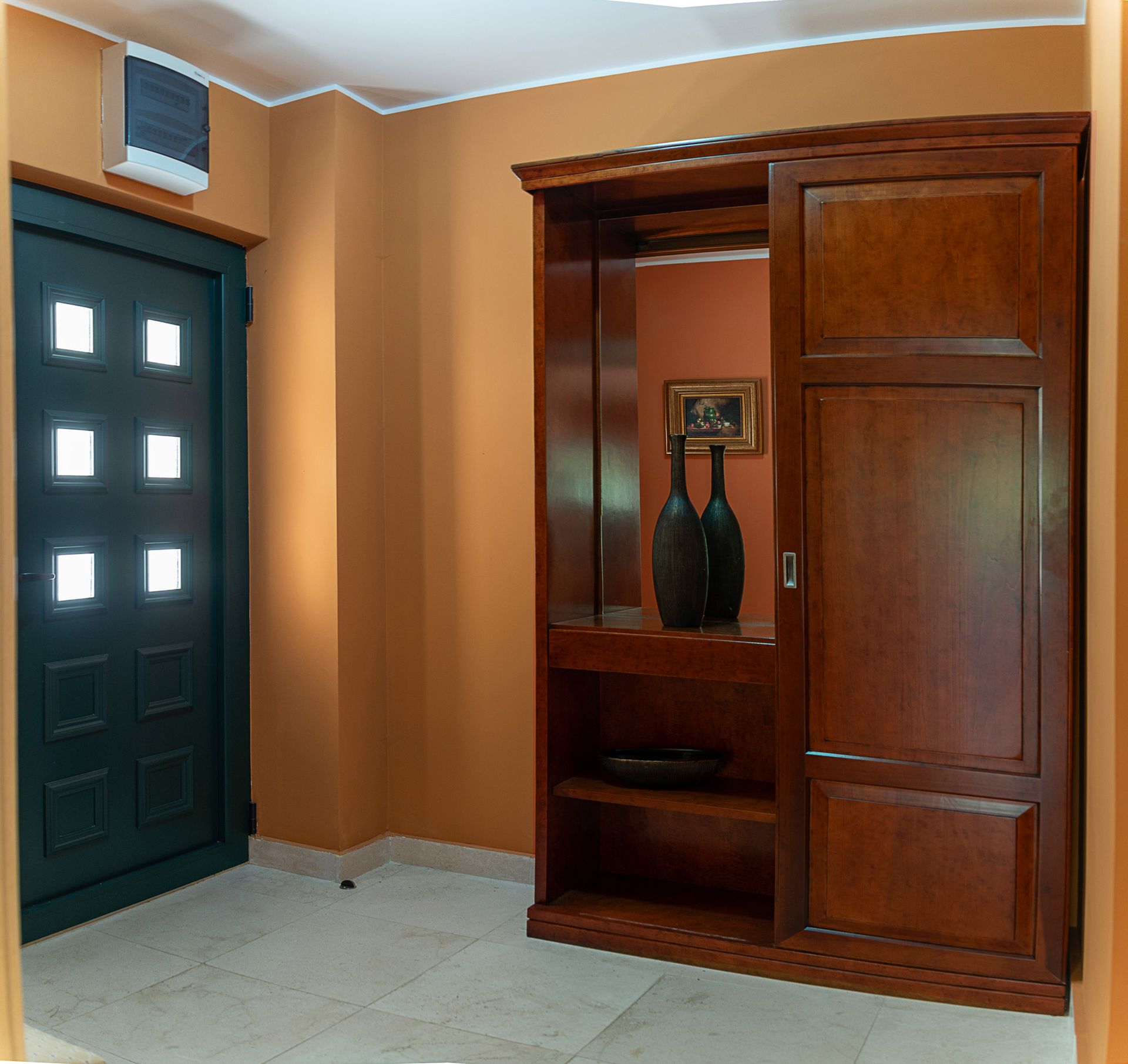Hallway in a townhouse in Lastva, Montenegro: dark wooden furniture, a mirror, decor, and an entry door with glazing.