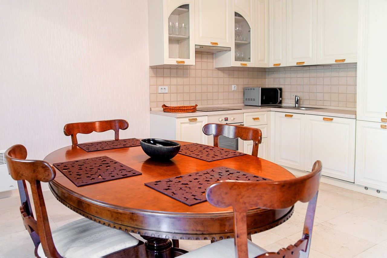 Kitchen with white cabinets and a wooden dining table in a townhouse, Lastva, Montenegro. Modern kitchen interior.