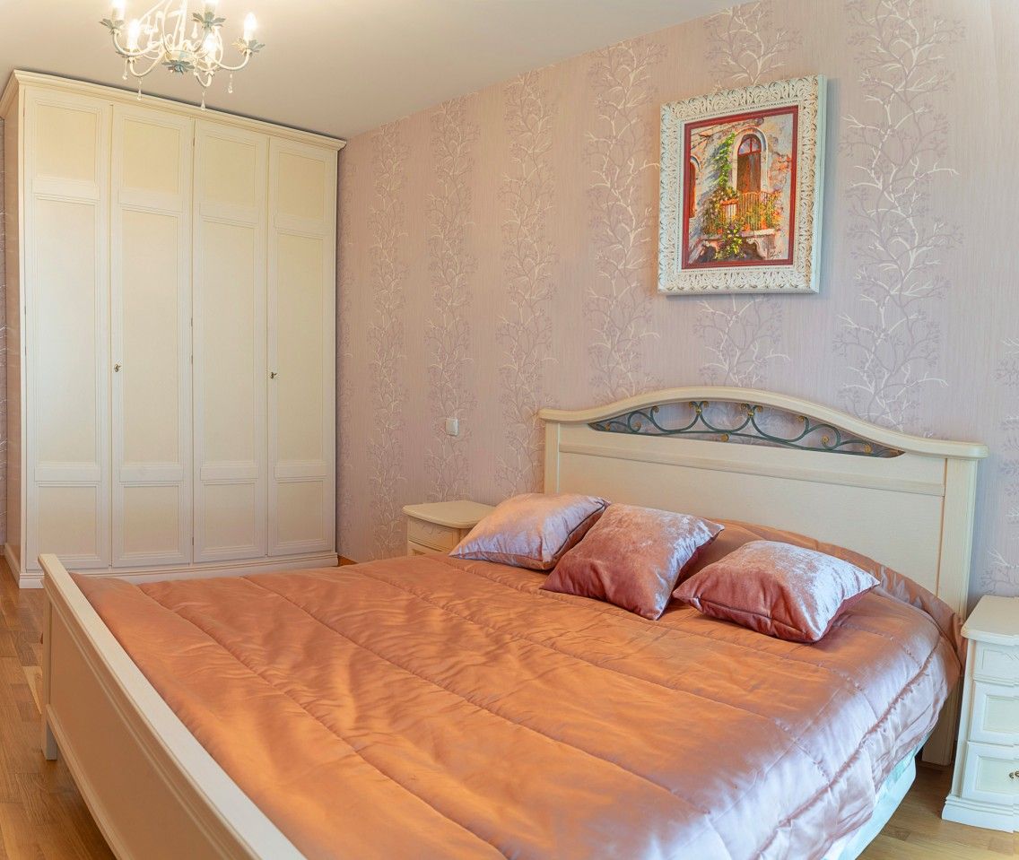 Cozy bedroom with a double bed and a light-colored wardrobe in a townhouse, Lastva, Montenegro. Classic interior.