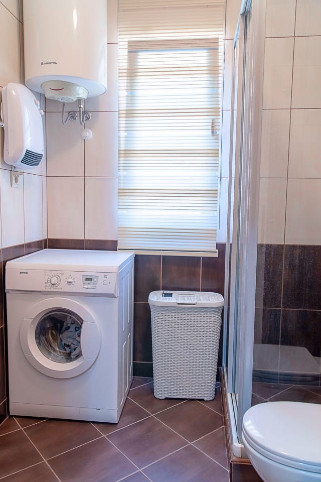 Bathroom in a townhouse in Lastva, Montenegro: washing machine, shower cabin, water heater, and tiled finish.