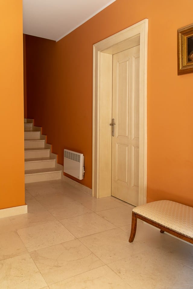 Townhouse hallway interior in Lastva, Montenegro: a light staircase, beige tile, and orange walls.