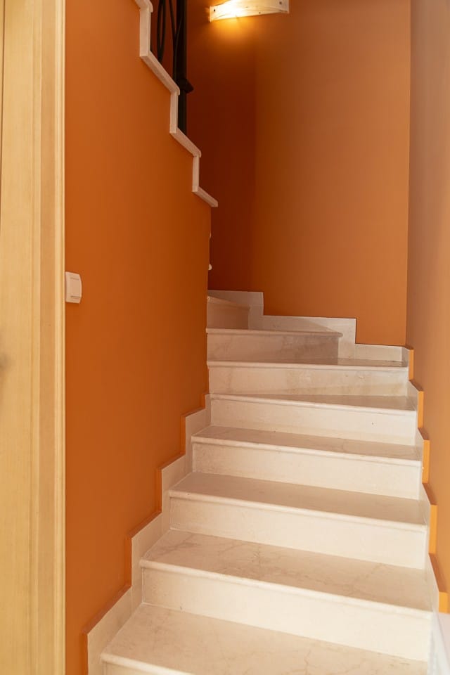 Marble staircase in a house interior in Lastva, Montenegro: light steps against bright orange walls.