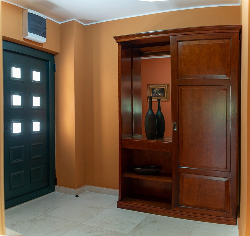 Townhouse hallway in Lastva, Montenegro: dark wooden furniture, a mirror, and an entrance door with glass panels.