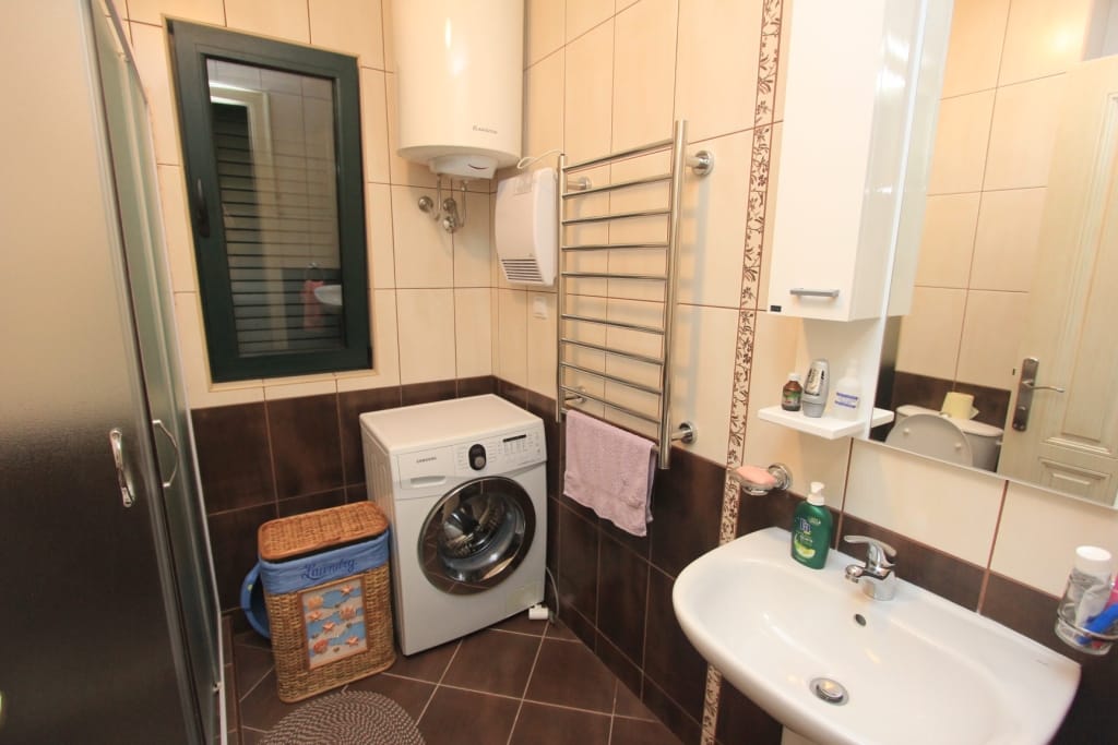 Bathroom in a townhouse, Lastva, Montenegro: shower cabin, washing machine, water heater, and tiled finish.