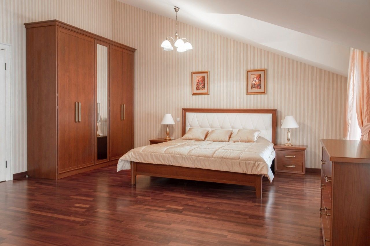 Cozy bedroom in a townhouse in Lastva, Montenegro: double bed, wooden wardrobe, and parquet flooring in the interior.