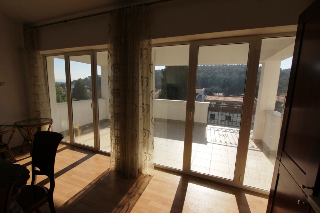 Living room with panoramic windows and access to the terrace in a mini-hotel, Sutomore, Montenegro. View of the mountains and the city.