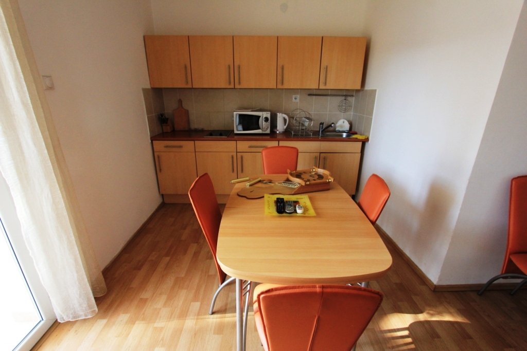 Kitchen with dining area and orange chairs in a mini-hotel, Sutomore, Montenegro. Bright interior with wooden furniture.