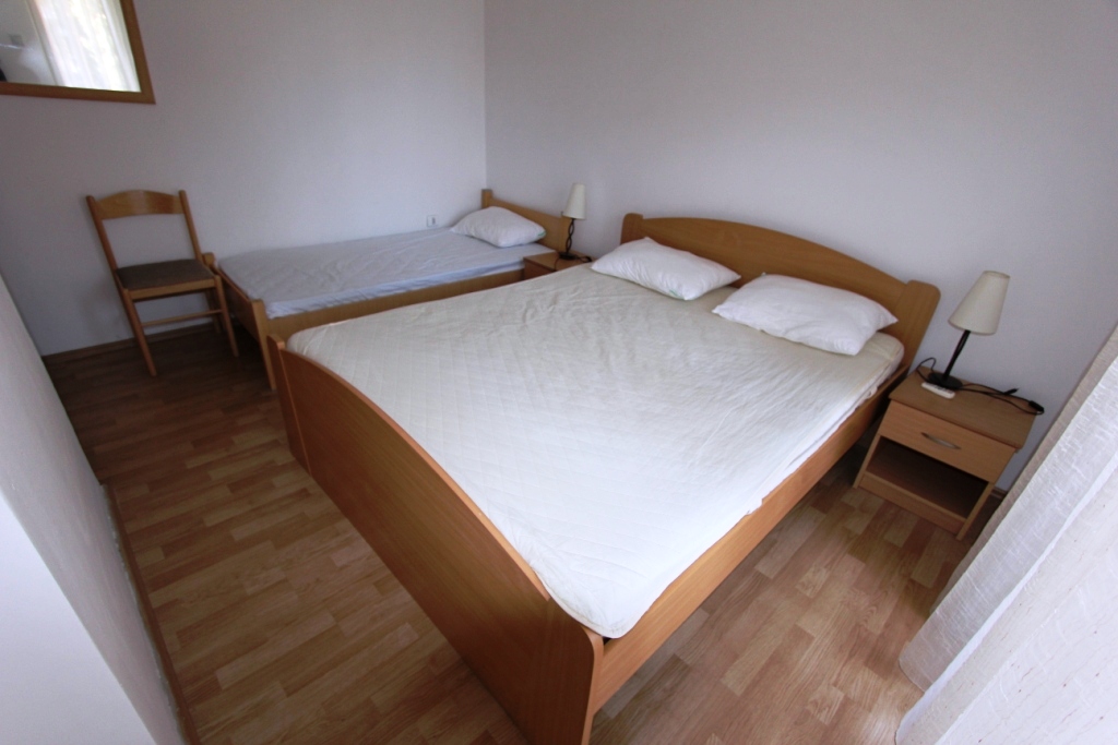 Bedroom in a mini-hotel in Sutomore, Montenegro: double and single beds, wooden furniture, bright interior.