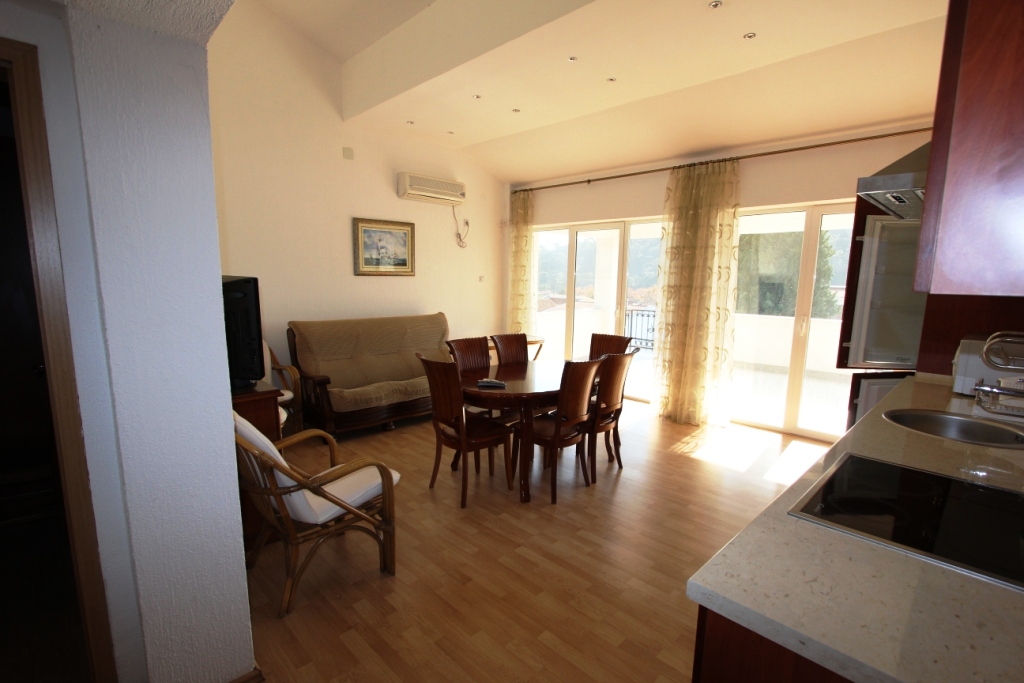 Living room with dining area and kitchen in a mini-hotel, Sutomore, Montenegro: bright interior, panoramic windows, and a terrace.
