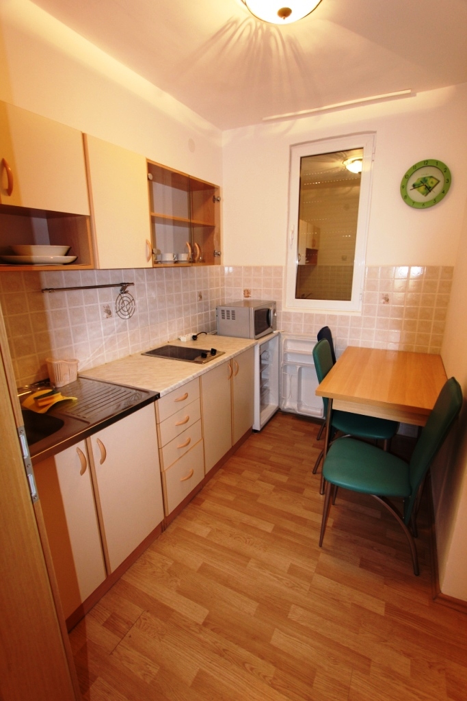 Compact kitchen in a mini-hotel in Sutomore, Montenegro: light-colored cabinets, dining area, and appliances.