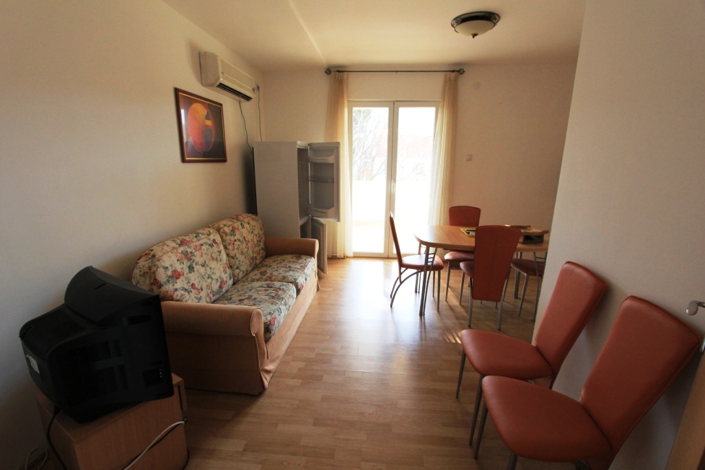 Living room in a mini-hotel in Sutomore, Montenegro: floral-print sofa, dining area, and access to the terrace.