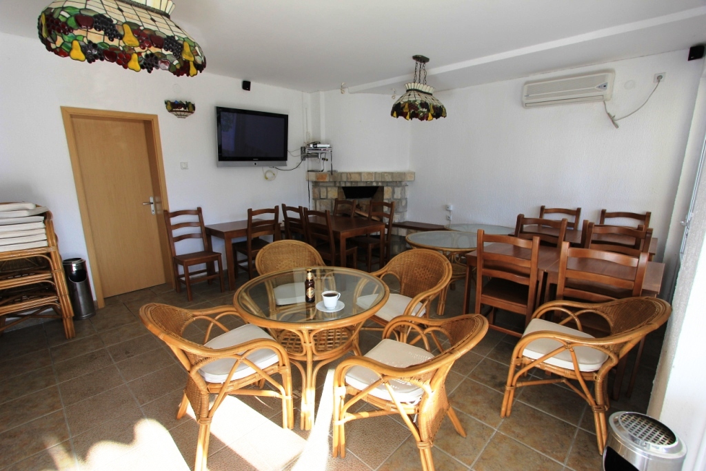 Living room in a mini-hotel in Sutomore, Montenegro: wicker chairs, wooden tables, a fireplace, and stained-glass lamps in the interior.