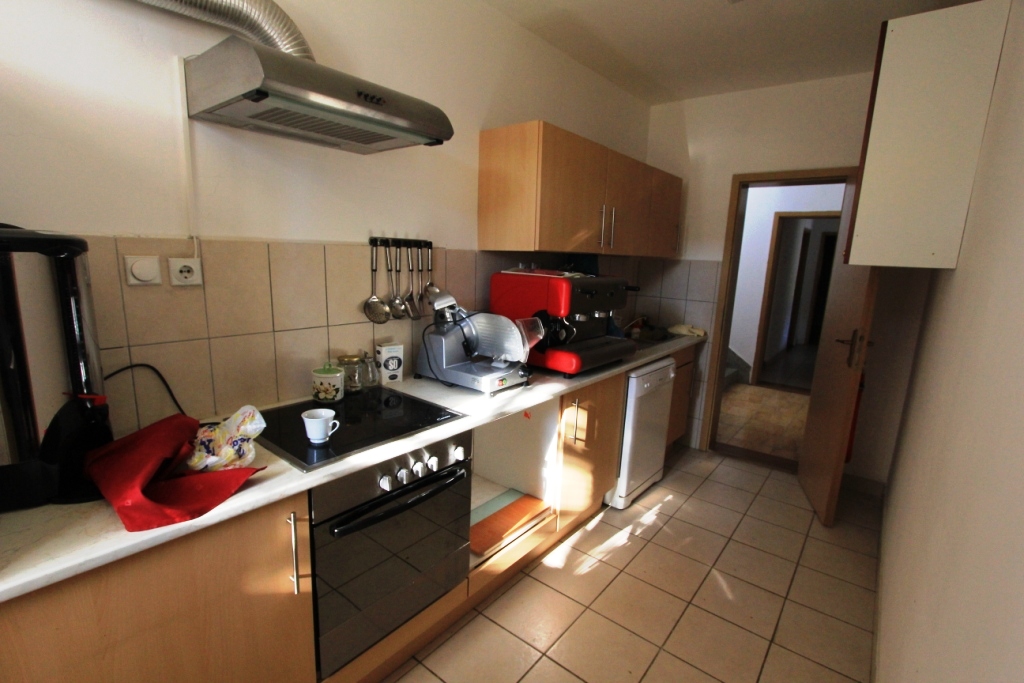 Kitchen in a mini-hotel in Sutomore, Montenegro: built-in appliances, light-colored cabinets, tiled floor, and a kitchen backsplash.