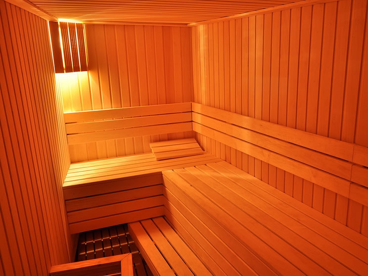 Modern wooden sauna at a hotel in Petrovac, Montenegro: steam room interior with benches and warm lighting.